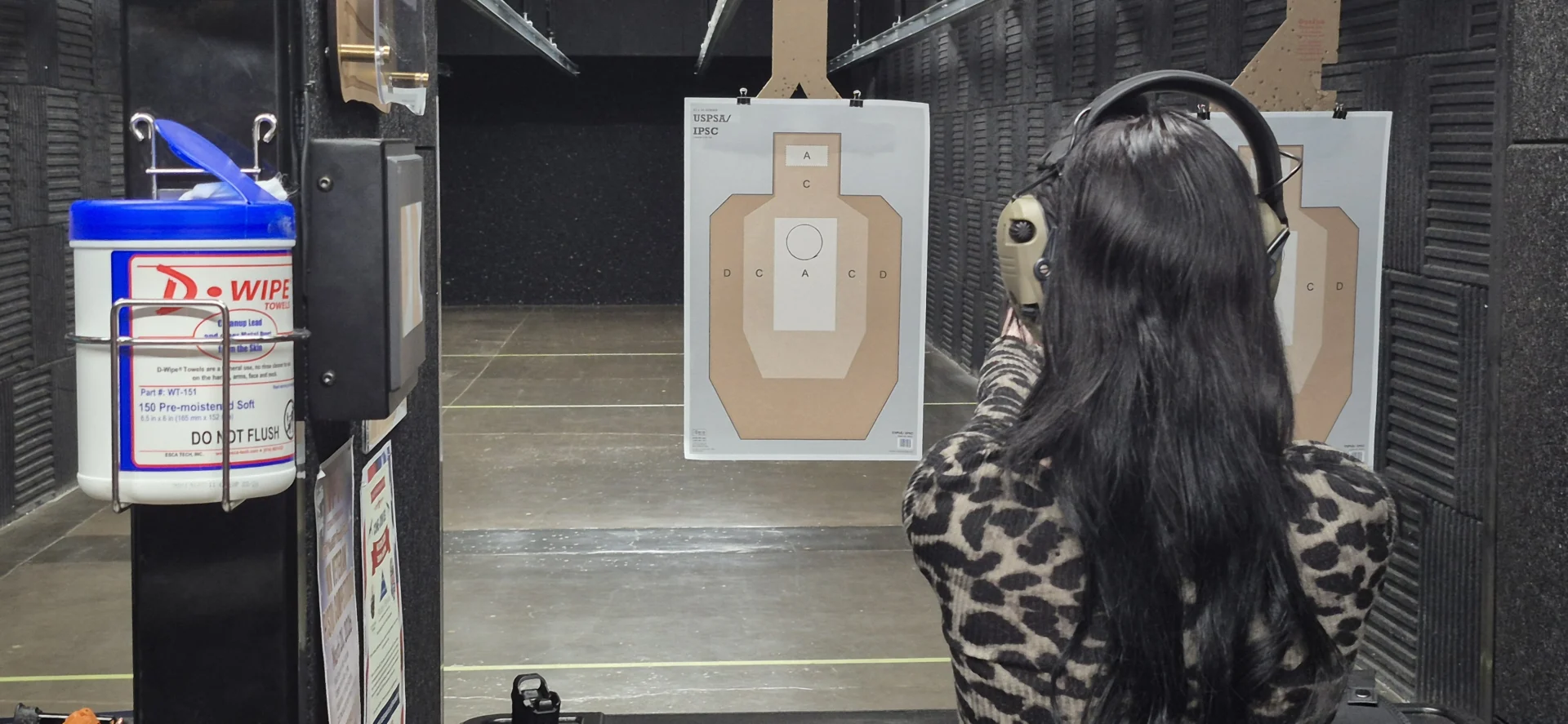 Shooter aiming at a paper target in an indoor range lane
